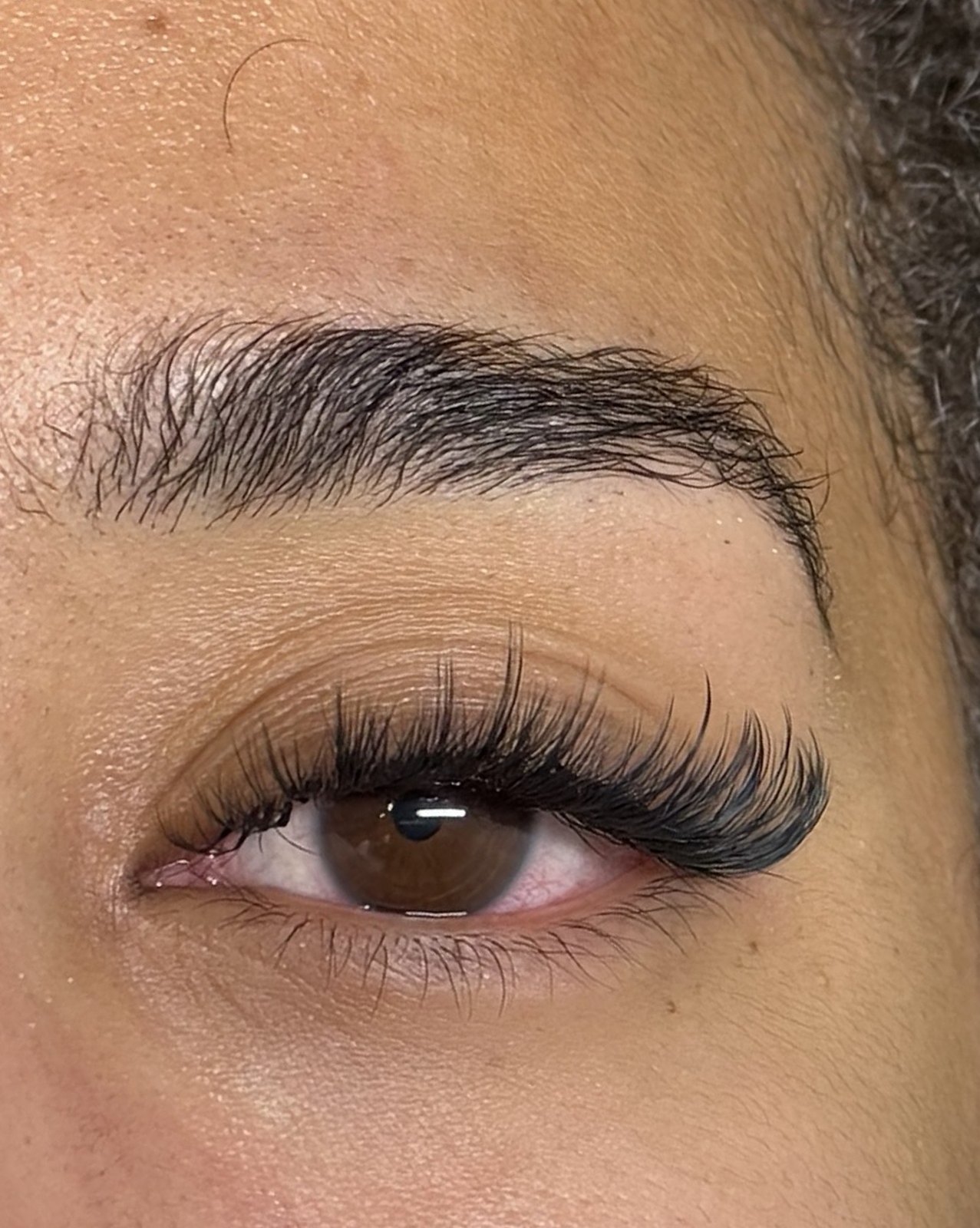 Close-up van een volle wimperset onder een verzorgde wenkbrauw
