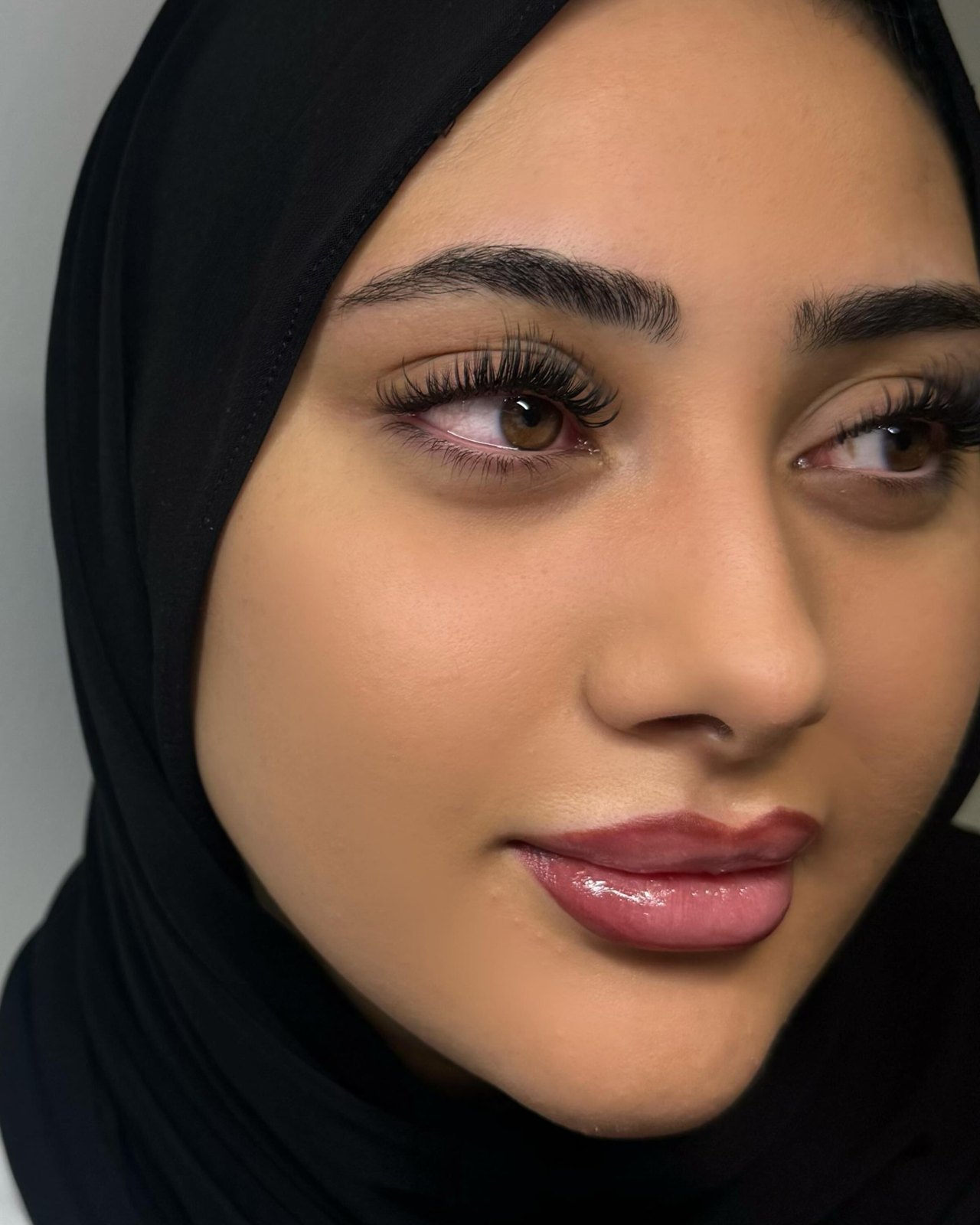 Klant met een wispy doll eye wimperset, rechtop tegen een lichte muur